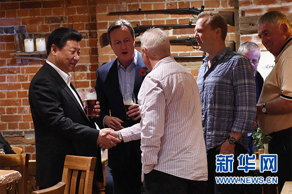 這是習近平與卡梅倫飲啤酒，并同當?shù)孛癖娊徽?。新華社記者 饒愛民 攝